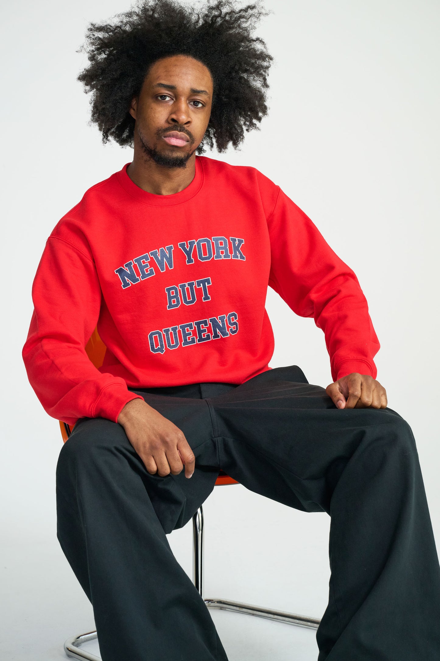 Person wearing a red sweatshirt with text, sitting on a chair against a white background