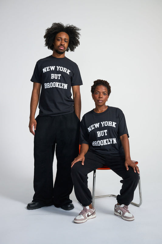 Two people wearing black t-shirts with 'New York But Brooklyn' text on a white background